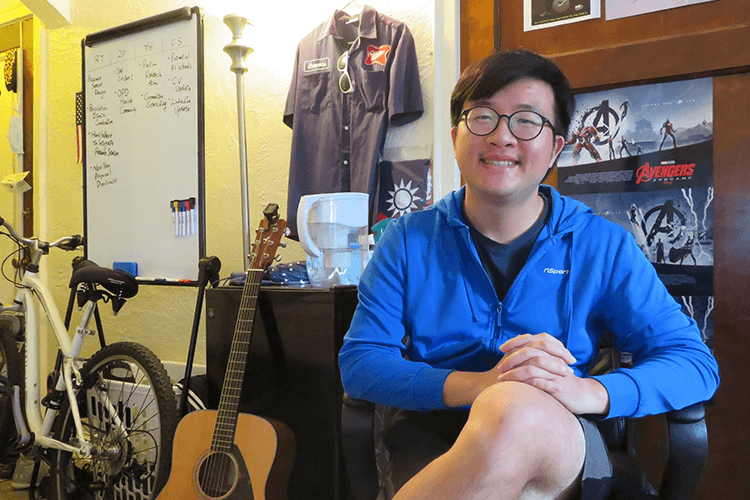 Student in dorm room with bike and guitar