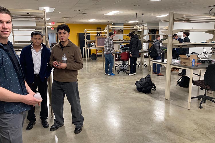 A half-dozen young men socialize in a maker space. A half-dozen young men socialize in a maker space.