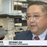 A middle-age Asian man speaks with a news reporter who is not visible.