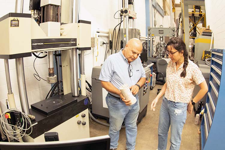 Professor Habib Tabatabai shows a student how a sample will be tested in the Structural Engineering Lab