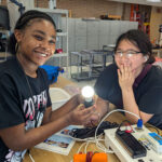 Image of two female students participating in the EnQuest camp who learned how to build a solar powered light.
