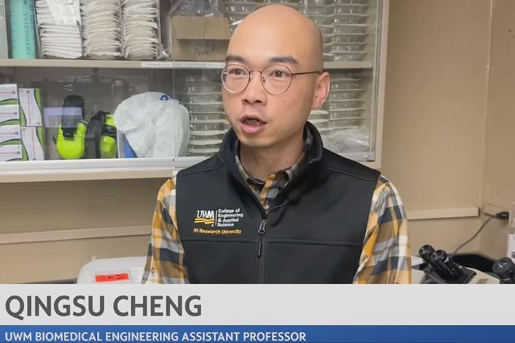 Video screen shot of a bald man with glasses and wearing a UWM vest speaking to the camera.
