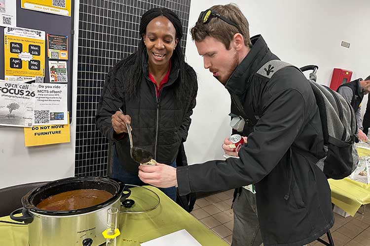 A black woman serves chili to a student in a dark jacket.