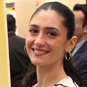 Headshot of a young woman with hoop earrings and dark hair in a ponytail. 