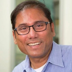 A headshot of a man with glasses and a little dark hair and light blue shirt.
