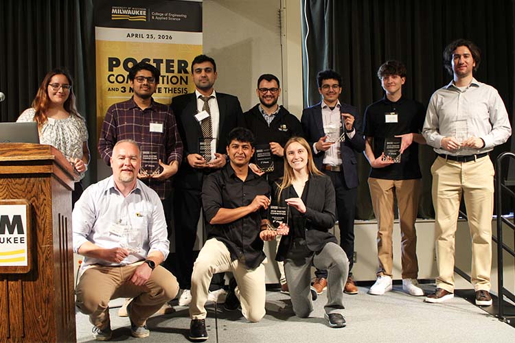 A group shot of 10 people each holding an awards plaque. The three in front are on one knee.