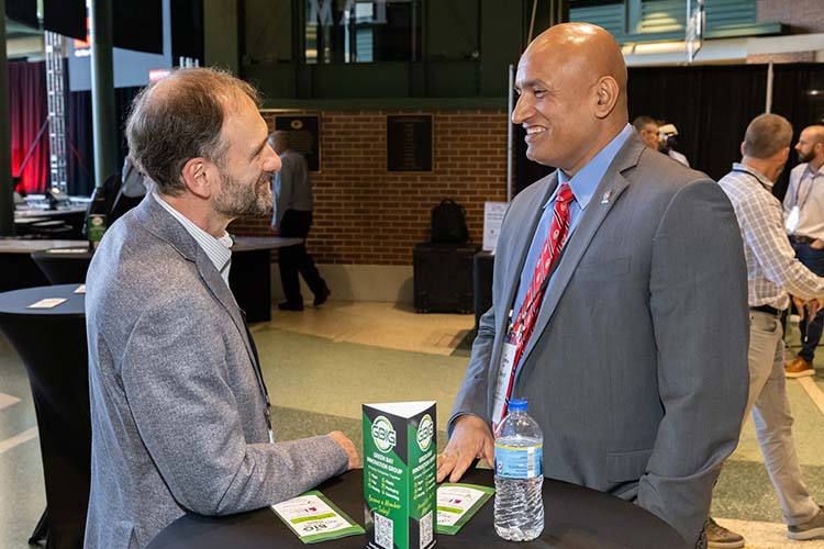 Two men in gray suits face each other. The one on the left has a beard and the one on the right is bald. Two men in gray suits face each other. The one on the left has a beard and the one on the right is bald.