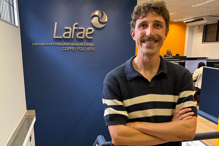A man with a mustache and navy striped shirt looks at the camera
