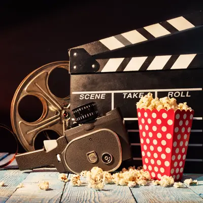 box of popcorn, movie reel, and sound clapper on table
