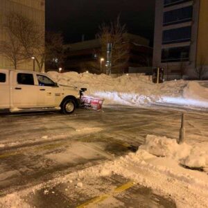 Picture of UWM's plow after having successfully cleared large amounts of snow off of the parking lot. The picture was taken during the nighttime, showing the service worker's dedication towards maintaining the campus.