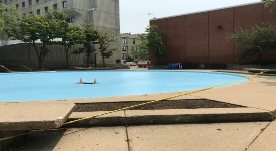 Empty fountain with a blue bottom, orange and white cones in the middle, and yellow caution tape around the outside