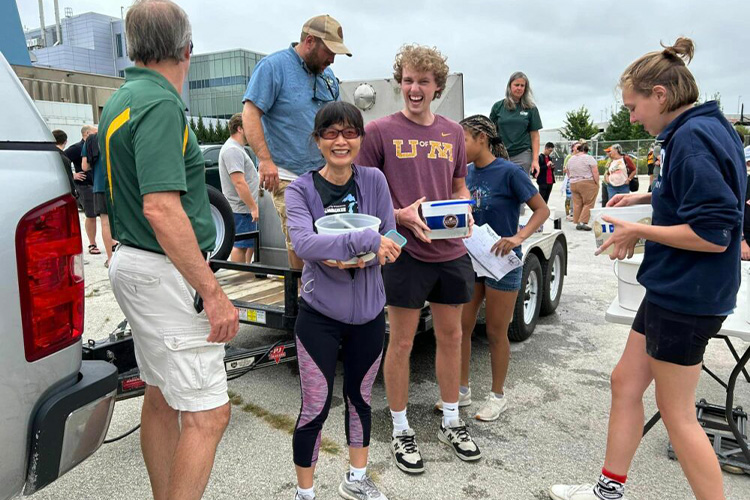 Dong Fang Deng and Sturgeon Fest attendees hold buckets of baby sturgeon preparing to release them into the Milwaukee Harbor.