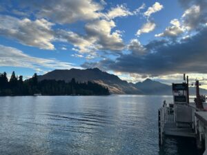 A body of water with clouds overhead and mountains in the distance.