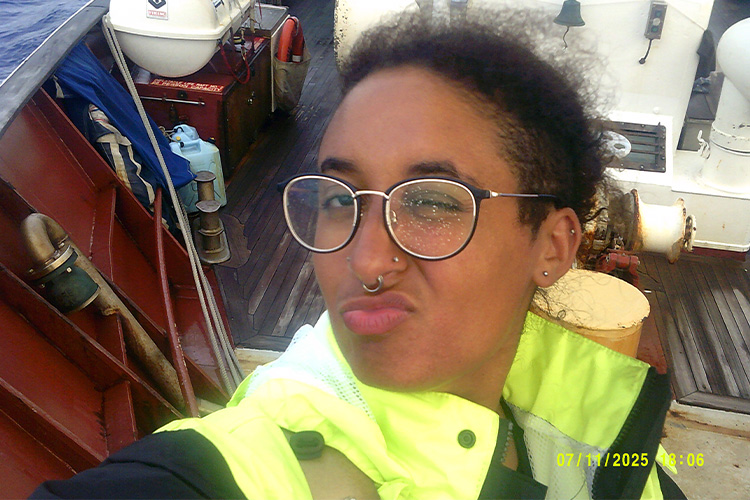 A person is on a ship wearing a bright yellow reflective vest.