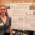 A woman is standing next to a poster.