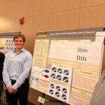 Three people are standing next to a research poster.