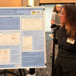 A person is talking to another person while looking at a poster.