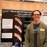 A man is standing in front of a poster.