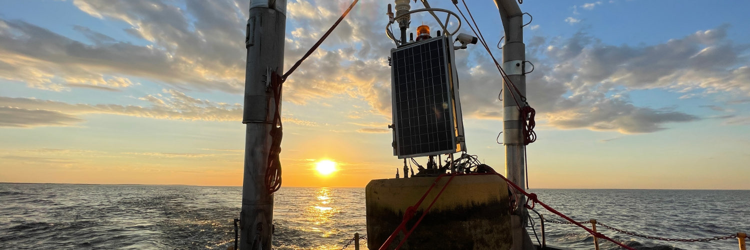 Buoy getting ready to be deployed A solar-powered monitoring buoy rests on a vessel’s deck as the sun sets over open water.