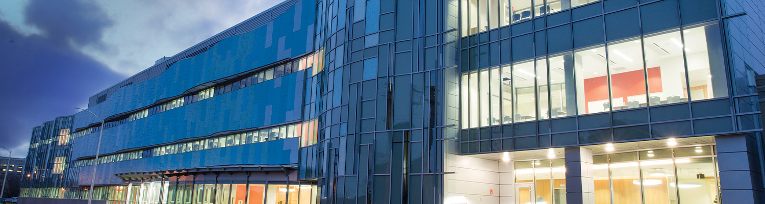 Exterior of the modern School of Freshwater Sciences building at dusk, with illuminated windows beneath a cloudy sky.