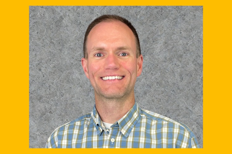 Clark Evans smiles behind a gray background.