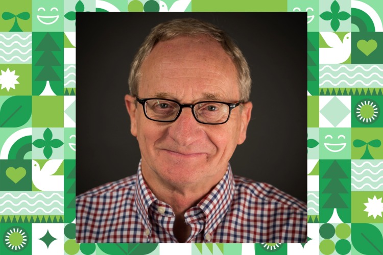 Larry Nielsen smiles in front of a dark background. Behind there is a patterned green background.
