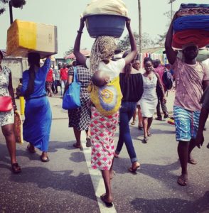 Locals crossing the street to shop and sell goods at the open air market in central Accra