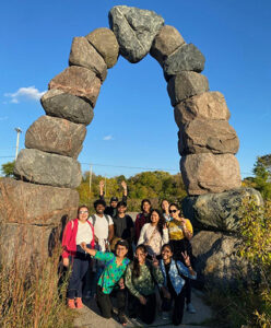 Group of UWM students hiking under an arch built by rocks.