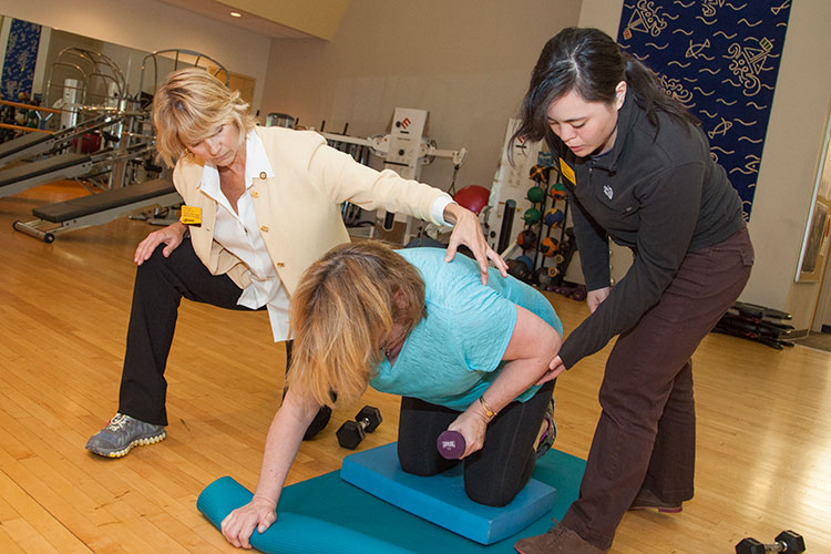 Doctor of Physical Therapy student and Professor working with a woman on therapeutic exercises.