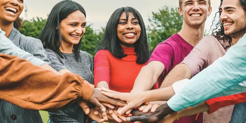 people in a circle with hands touching in the middle