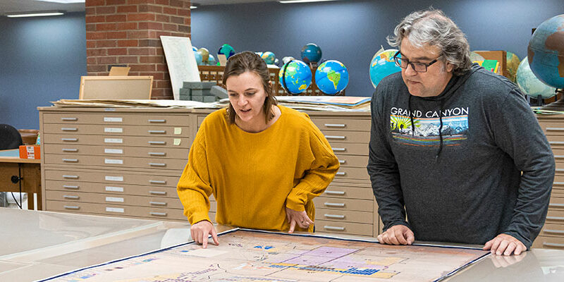 Student Interna and Librarian working in with a map in the UWM Library