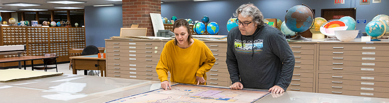Student Interna and Librarian working in with a map in the UWM Library