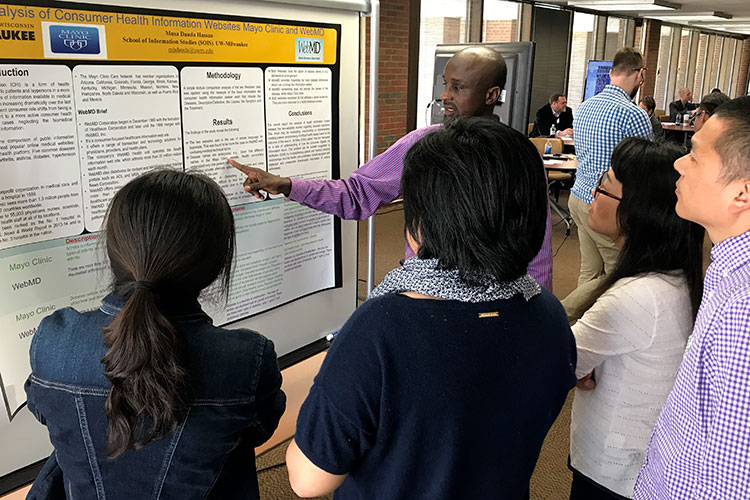 students at research event gathered around a poster discussing content