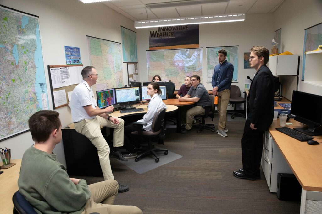 Students gathered in discussion in a weather forecasting office