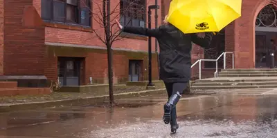 student walking in rain with umbrella