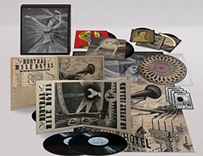 Image shows artwork from the boxset "The Collected Works of Neutral Milk Hotel," including the box (black and white image of a dancing woman), posters (showing sepia and black images in the style of an old theater handbill, postcards, and album covers.