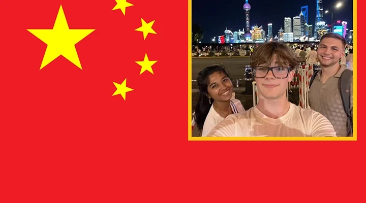 Three students take a selfie in a busy nighttime city