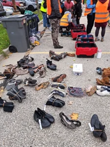 Piles of shoes are stacked on the pavement waiting to be distributed to unhoused people.