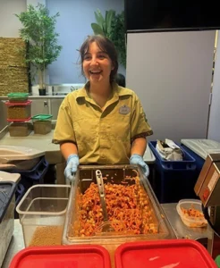 A young white woman mixes ground up food in a clear plastic bin.
