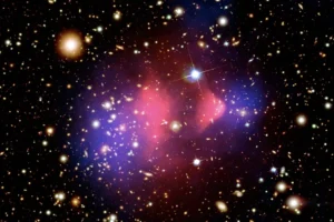 An image of galaxies dotting the blackness of space, with a pink and blue cloud indicating where scientists think dark matter is pulling a cluster of galaxies together.