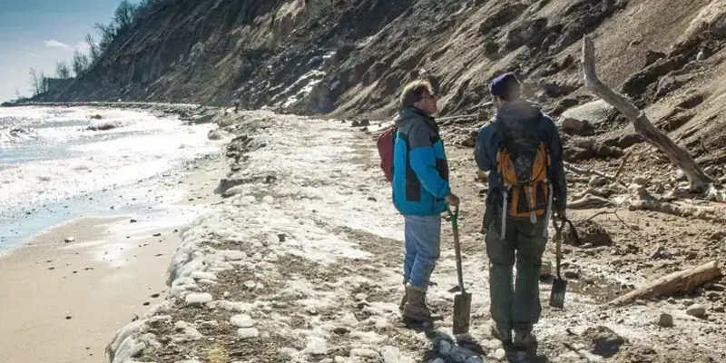 two people standing on lakeshore with tools