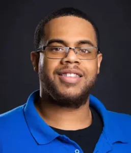 Headshot of a Black man wearing a blue polo shirt and glasses.