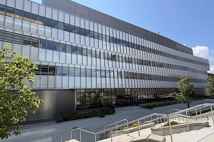 A long gray building with three stories of banks of glass windows.