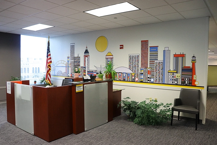 An office lobby with a desk and a mural of the Milwaukee city skyline on the wall behind the desk.