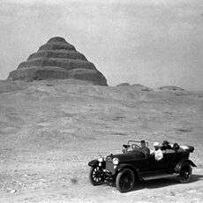 older model car in front of pyramid