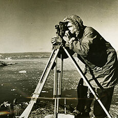 Photographer with camera on tripod wearing winter coat