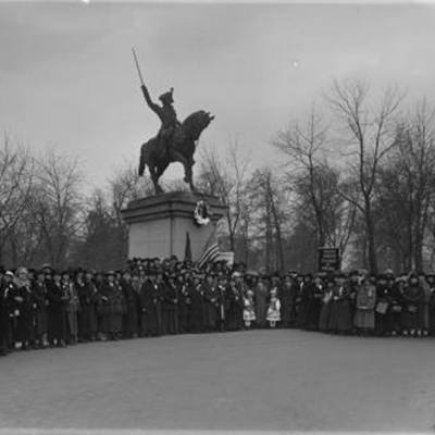 Statue of man on horse flanked by crowd posing for camera
