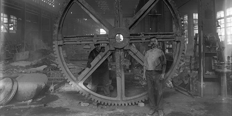 Image of men in front of giant round machine part