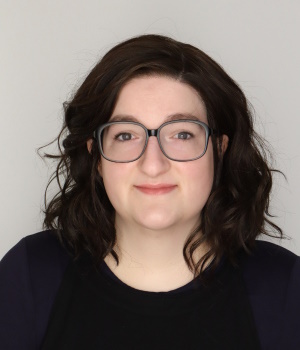 A woman wears a black top and glasses.