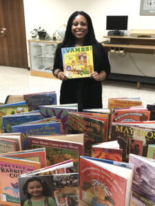 photo of Tiffany Thornton, outreach & community engagement librarian at the UWM Libraries, with a selection of books from the Libraries' Américas collection.